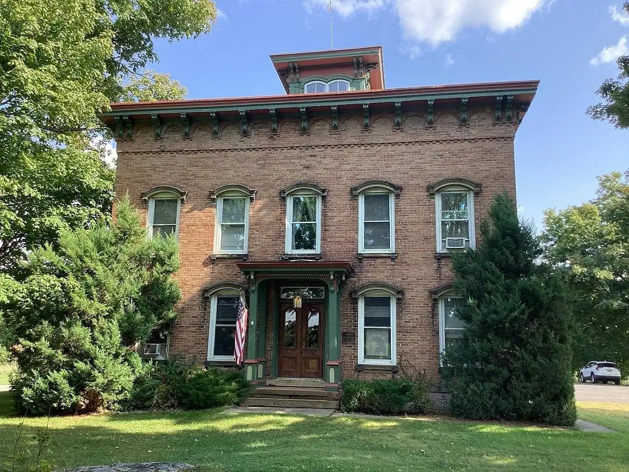 The Tallman House from the street: a brick Italianate house with a cupola and a flag out front